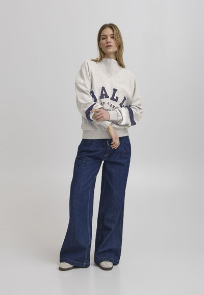 Lys grå hettegenser med "BALL" grafikk i mørk lilla, paret med vide denimjeans i mørk farge. Lett tekstur; avslappet design.