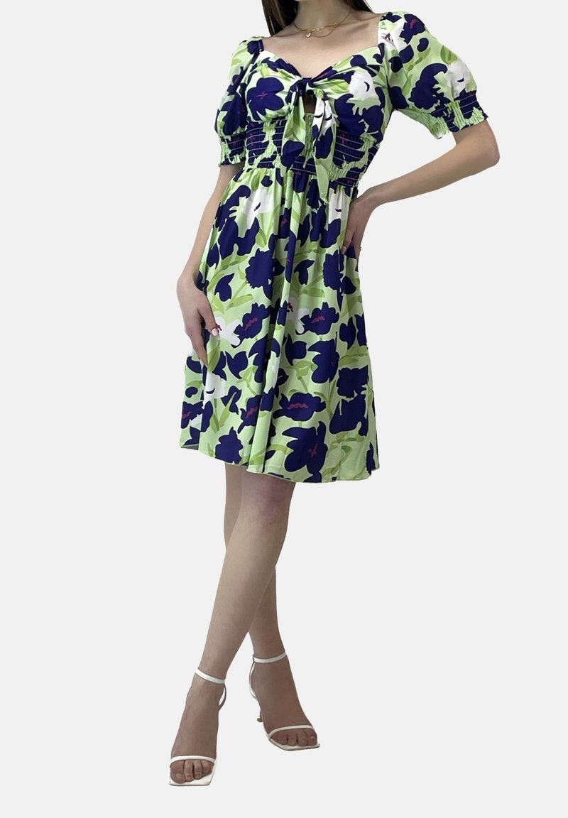 Kortärmad klänning i ljusgrön med blommönster i mörkblått och vitt. Har en smockad bodice och en knytdetalj vid halsringningen.