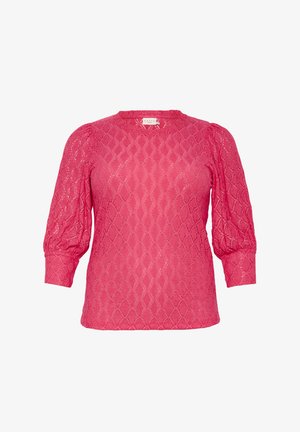 Blouse rose texturée avec un motif en diamant, col rond et manches bouffantes. Le matériau est léger et semi-transparent.