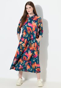 Šaty s květinovým potiskem v živých odstínech oranžové, růžové a tyrkysové barvy, tříčtvrteční rukávy a boční kapsy, vyrobené z lehké látky.