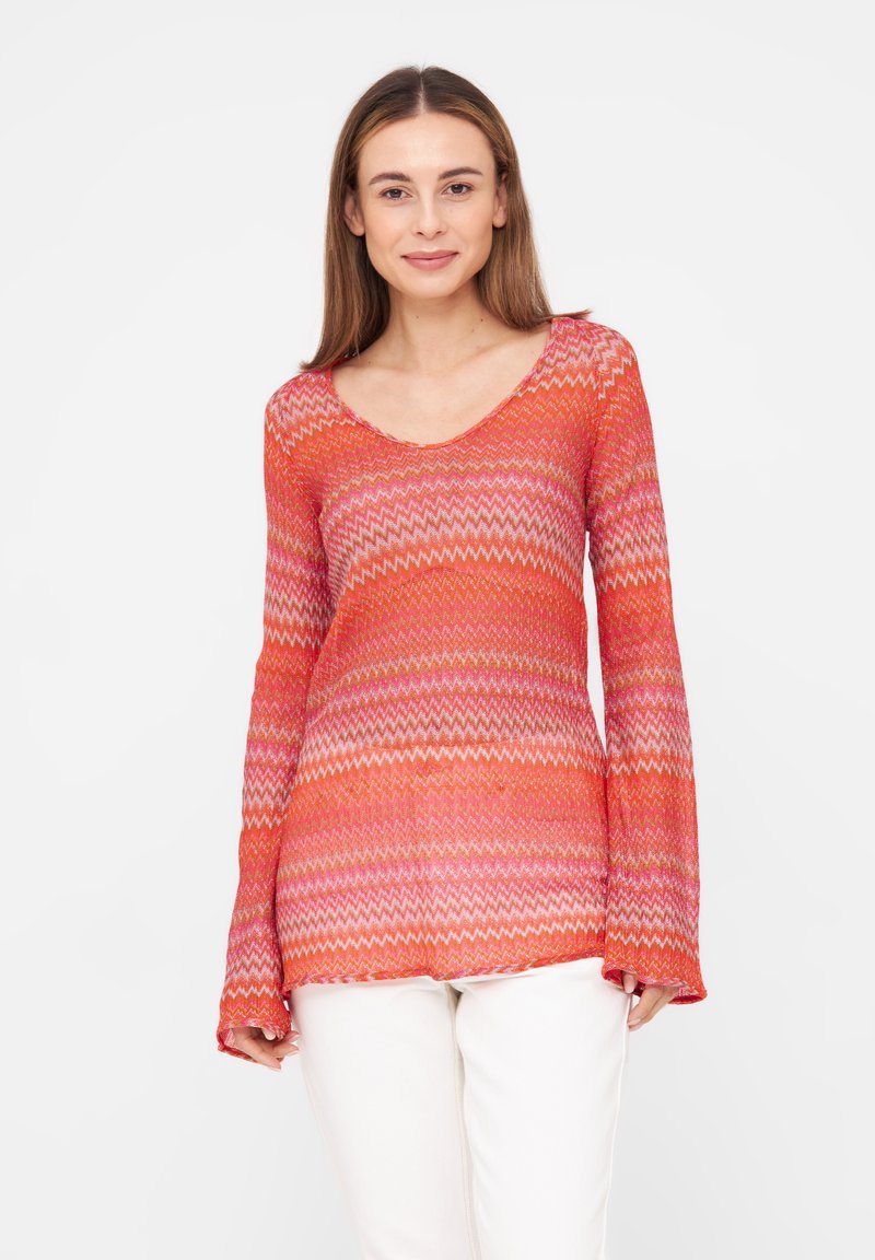 Langarm-V-Ausschnitt-Oberteil in leuchtendem Orange mit einem Zickzackmuster in Pink und Weiß. Leichtes, durchsichtiges Material mit ausgestellten Ärmeln.