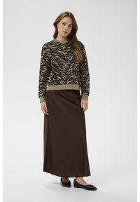 Svetr v béžovo-černém cikcak vzoru s kulatým výstřihem; kombinovaný s dlouhou hnědou sukní; černé baleríny. Hladká textura, ležérní střih.