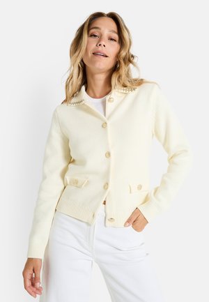 Cardigan abotonado de punto en suave amarillo pastel, con cuello tipo solapa, dos bolsillos frontales y detalles decorativos de botones.