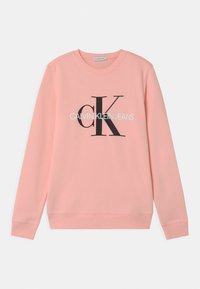 Růžová mikina s dlouhými rukávy, žebrovanými manžetami a lemem. Na přední straně je černé grafické logo: "cK CALVIN KLEIN JEANS" uprostřed.