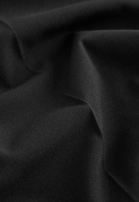 Tissu noir lisse avec des plis subtils et une texture douce, présentant des ombres délicates et des reflets sur la surface.