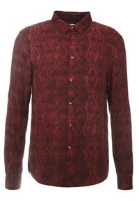 Chemise à manches longues boutonnée avec motif peau de serpent rouge et noir et col pointu.
