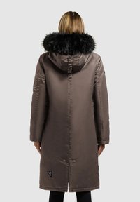 Brun lang parka med hætte beklædt med pels, glat tekstur, knaplukninger og et logo-patch på nederste venstre side.