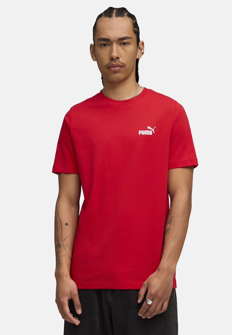 Rød bomulds T-shirt med rund hals og korte ærmer. Fremtrædende hvid Puma-logo på venstre bryst. Enkel design, almindelig pasform.