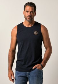 Top senza maniche di colore blu navy con scollatura tonda, dotato di una toppa rotonda sul lato sinistro del petto e di un tessuto strutturato.