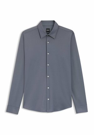 Chemise grise pour homme à manches longues avec col et sept boutons, posée à plat sur un fond blanc, étiquette visible à l'intérieur du col.