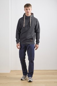 Mørkegrå hoodie med kengurulomme, lysebeige snore og et lædermærke. Sammen med navyblå bukser og grå sneakers.