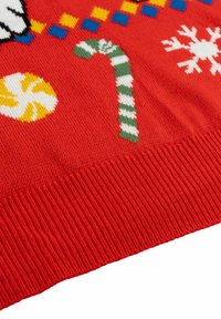 Maglione rosso lavorato a maglia con motivi festivi di una bastoncino di zucchero, menta piperita, fiocchi di neve e accenti geometrici multicolore. Orlo a costine.