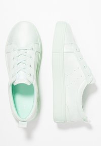 Jasno miętowe trampki o gładkiej powierzchni, z wyścielonym kołnierzem, z sznurowanym zapięciem i teksturowaną podeszwą z subtelnymi perforacjami.