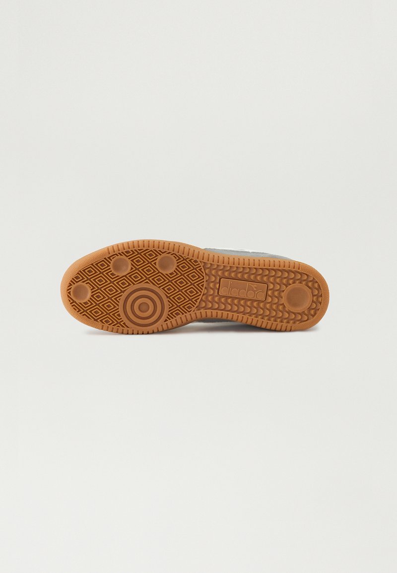 Semelle de chaussure en caoutchouc avec un motif brun texturé, comprenant des formes circulaires et en losange. Bords plats et arrondis pour une traction et une stabilité accrues.