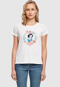 Hvit bomull t-skjorte med et cartoon-motiv av Snøhvit, omgitt av blomster og blader i pastellfarger. T-skjorten har kort erme og en avslappet passform.