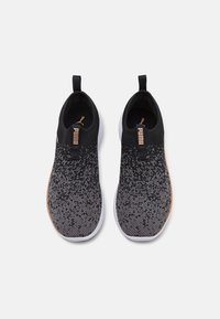 Chaussures de sport tricotées noires et grises avec un design dégradé, des languettes à l'arrière et des semelles blanches. Marquage Puma notable en or.