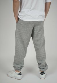 Gray sweatpants with tapered ankles, made from soft fabric, featuring side pockets. Paired with white sneakers with dark accents.