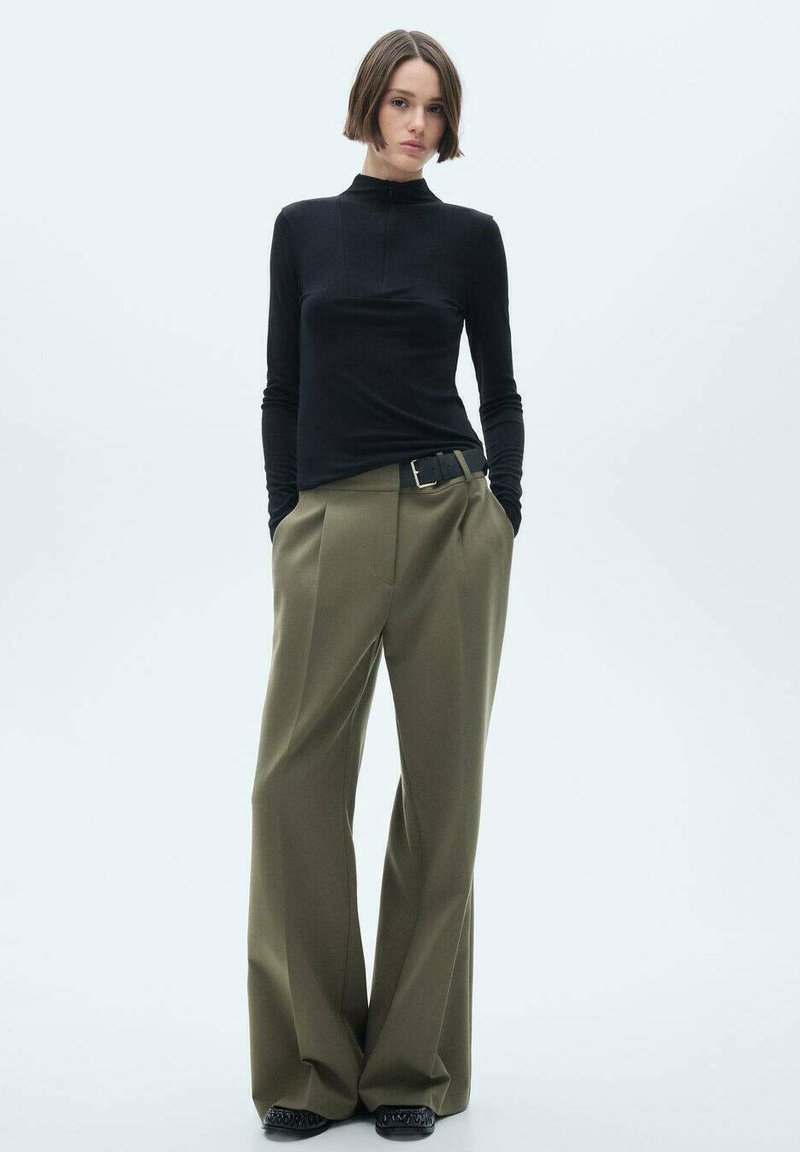 Black long-sleeve top with a high neckline, paired with olive wide-leg trousers and a black belt. Smooth texture, structured silhouette.