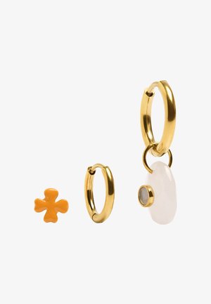 Jedna złota kolczyk kołowy, jedna mała pomarańczowa sztyft w kształcie kwiatu oraz jedna złota kolczyk kołowy z białym owalem i małym okrągłym zawieszonym.