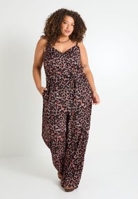 Mono negro con estampado de leopardo en rojo y rosa. Cuenta con un escote en V, tirantes finos, corte holgado y bolsillos laterales. Se llevan zapatos planos.