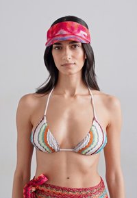 Bikini coloré avec un haut en triangle présentant des rayures ondulées orange, vert et gris ; visière rouge et bleue avec logo ; tissu texturé.