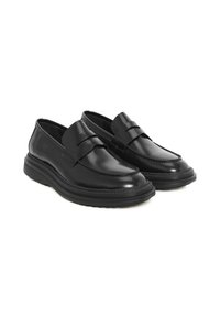 Mocasines de cuero negro con punta redondeada, detalles de costura y una suela de goma con plataforma. Presentan una correa decorativa a lo largo del empeine.