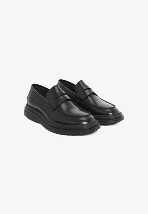 Mocassins en cuir noir avec un bout arrondi, des coutures décoratives et une semelle en caoutchouc à plateforme. Présente une bandoulière décorative sur le devant.
