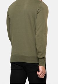 Olivově zelená mikina s kulatým výstřihem vyrobená z měkké látky, s žebrovanými manžetami a lemem, jednoduchým designem na zádech a bez viditelných log.