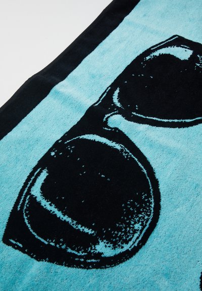 Turquoise beach towel featuring a large black sunglasses graphic. Soft texture with contrasting black trim along the edges.