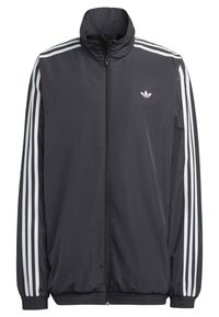 Czarna kurtka dresowa Adidas z pełnym zamkiem z przodu, białe trzy paski na rękawach oraz małe logo trefoil na lewej piersi.