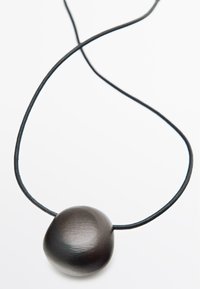 Black stone pendant on a thin black cord. Pendant is oval with a smooth matte finish, creating a sleek, modern appearance.