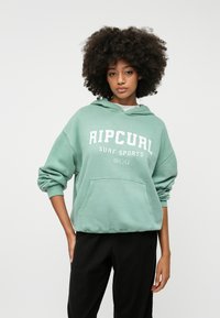 Mintgroene hoodie met de tekst "RIPCURL SURF SPORTS", een buidelzak en een losse pasvorm. Zachte stof en ribgebreide manchetten verhogen het comfort.