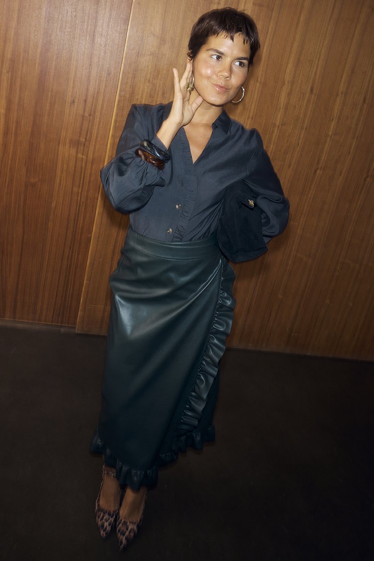 Marinblå blus med knappar och puffiga ärmar, kombinerad med en mörkgrön konstläderkjol med volangkant och leopardmönstrade klackskor.