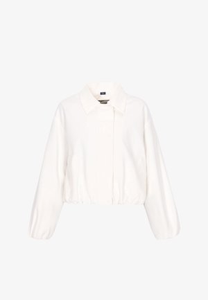 Fehér hosszú ujjú, rövidített dzseki gallérral, elasztikus szegéllyel és mandzsettával, valamint rejtett elülső záródással, egyszínű háttéren.