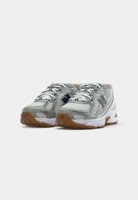 Par de zapatillas de running New Balance en gris y blanco con detalles de malla y suelas de goma en un fondo blanco.