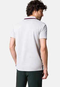 Szara koszulka polo z kołnierzykiem, posiadająca czerwone i granatowe paski, krótkie rękawy oraz lekko teksturowany materiał. Logo marki na plecach.