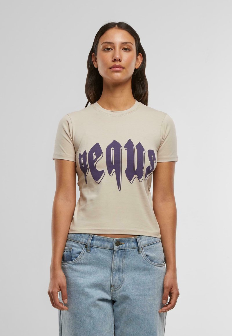 Camiseta de manga corta color beige con texto gráfico en púrpura. El diseño tiene un corte ajustado con cuello redondo y una textura de tela suave.