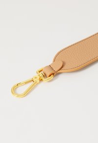 Leather strap in light beige, featuring a textured surface, with a gold-tone metal clip and accents, stitching visible along the edges.
