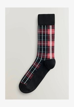 Mustri musta ja punane sokk, millel on valge ja helesinine ruuduline mustriga, paigutatud helesinisele hallile taustale.