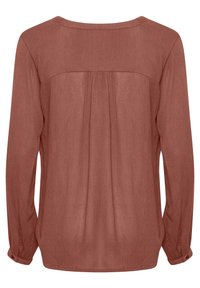 Langärmlige Bluse aus rostfarbener, strukturierter Stoff. Mit gefaltetem Rücken, Rundhalsausschnitt und geknöpften Manschetten.