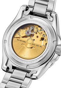 Nerūdijančio plieno laikrodžio galas su matomu auksiniu mechanizmu, kuriame yra sudėtingi mechanizmai ir purpurinė brangakmenis. Išgraviruoti detalės nurodo modelį ir medžiagas.