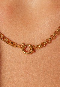 Gouden ketting met ronde schakels en een ronde sluiting, met een gepolijste afwerking en een gladde textuur.