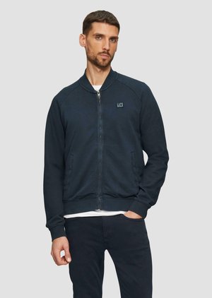 Navy blue zip-up bomber jacket with ribbed cuffs and hem, featuring side pockets and a small logo on the chest. Smooth cotton blend fabric.
