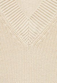 Krämfärgad stickad tröja med V-ringning, med texturerad ribbad design och mjukt, tjockt garn.