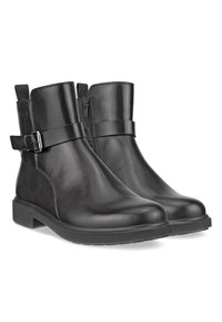 Botas de cuero negras hasta el tobillo con un acabado suave, que cuentan con una cremallera lateral, una correa ajustable con un hebilla de plata y una suela de goma plana.