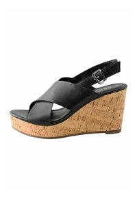 Black leather wedge sandal with cross-strapped design. Cork platform adds texture and height. Adjustable ankle strap with buckle detail.