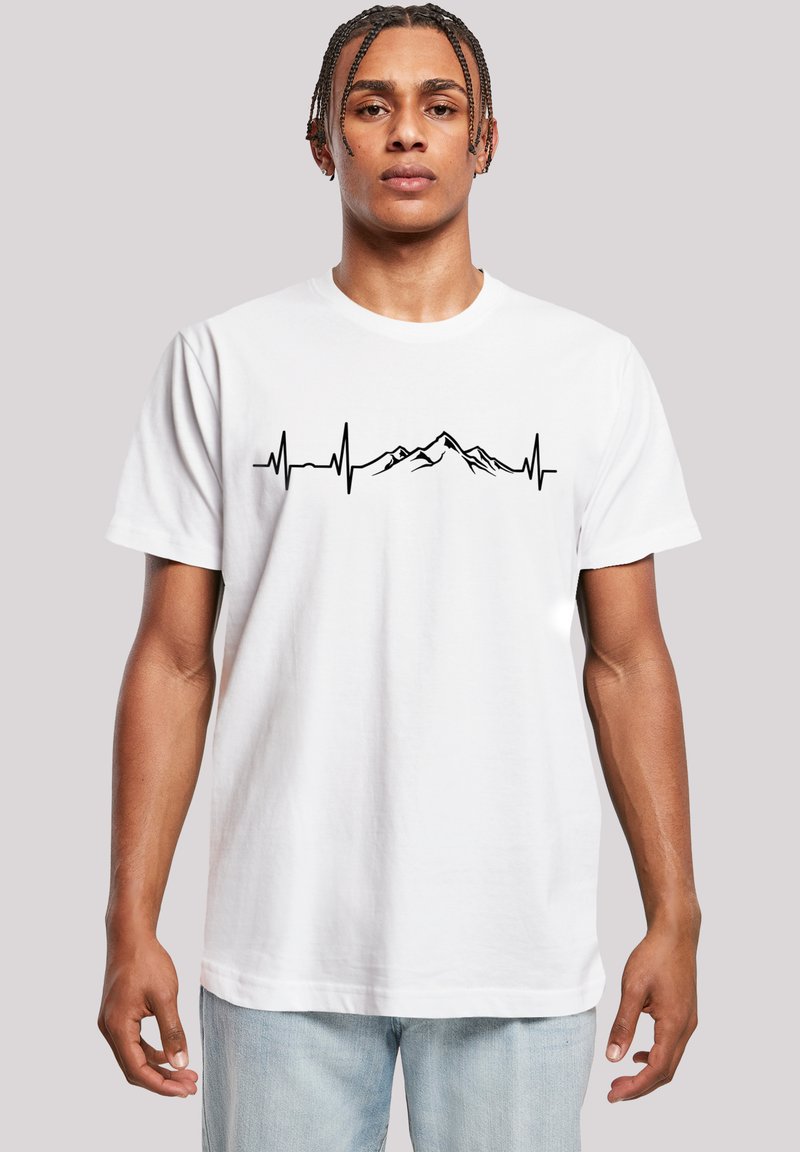 White cotton t-shirt featuring a black heartbeat line graphic with mountain peaks, round neck, and short sleeves. Smooth texture.