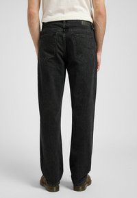 Svarte denimbukser med avslappet passform, med to baklommer og synlige sømdetaljer. Stoffet har en lett teksturert overflate.