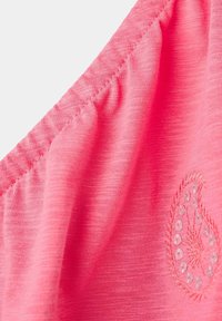 Tissu rose avec bord élastique et un petit détail pailleté et brodé en forme de cœur en bas à droite.