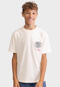 Short-sleeve ivory cotton t-shirt featuring a logo and text in black and red, relaxed fit, with a round neckline and subtle texture.